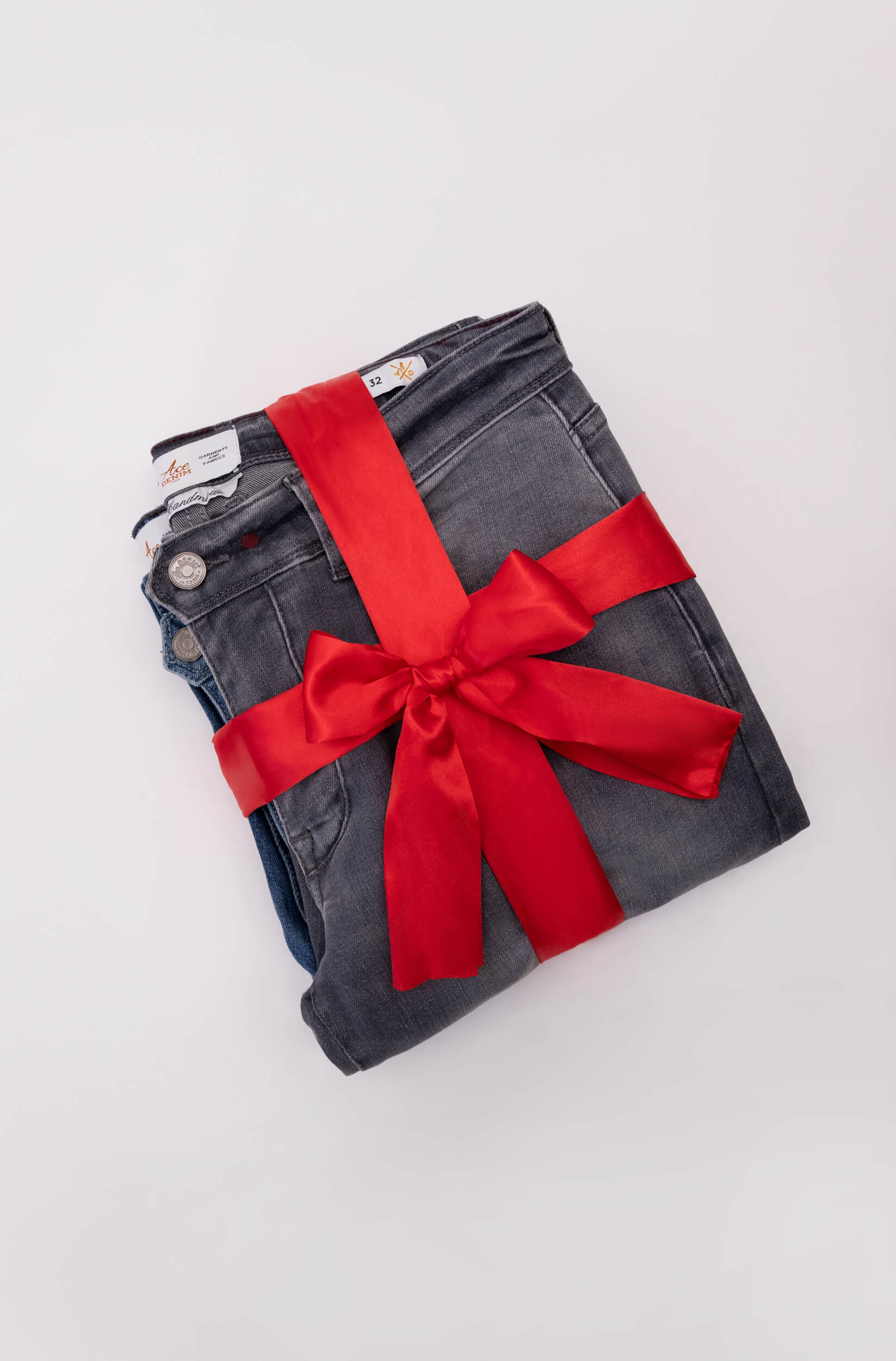 Jeans gris dans un ruban rouge de paquet cadeau de noël