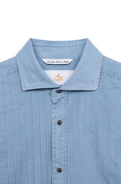 Close-up of the spread collar and pleated bib of the light blue cotton tuxedo shirt.